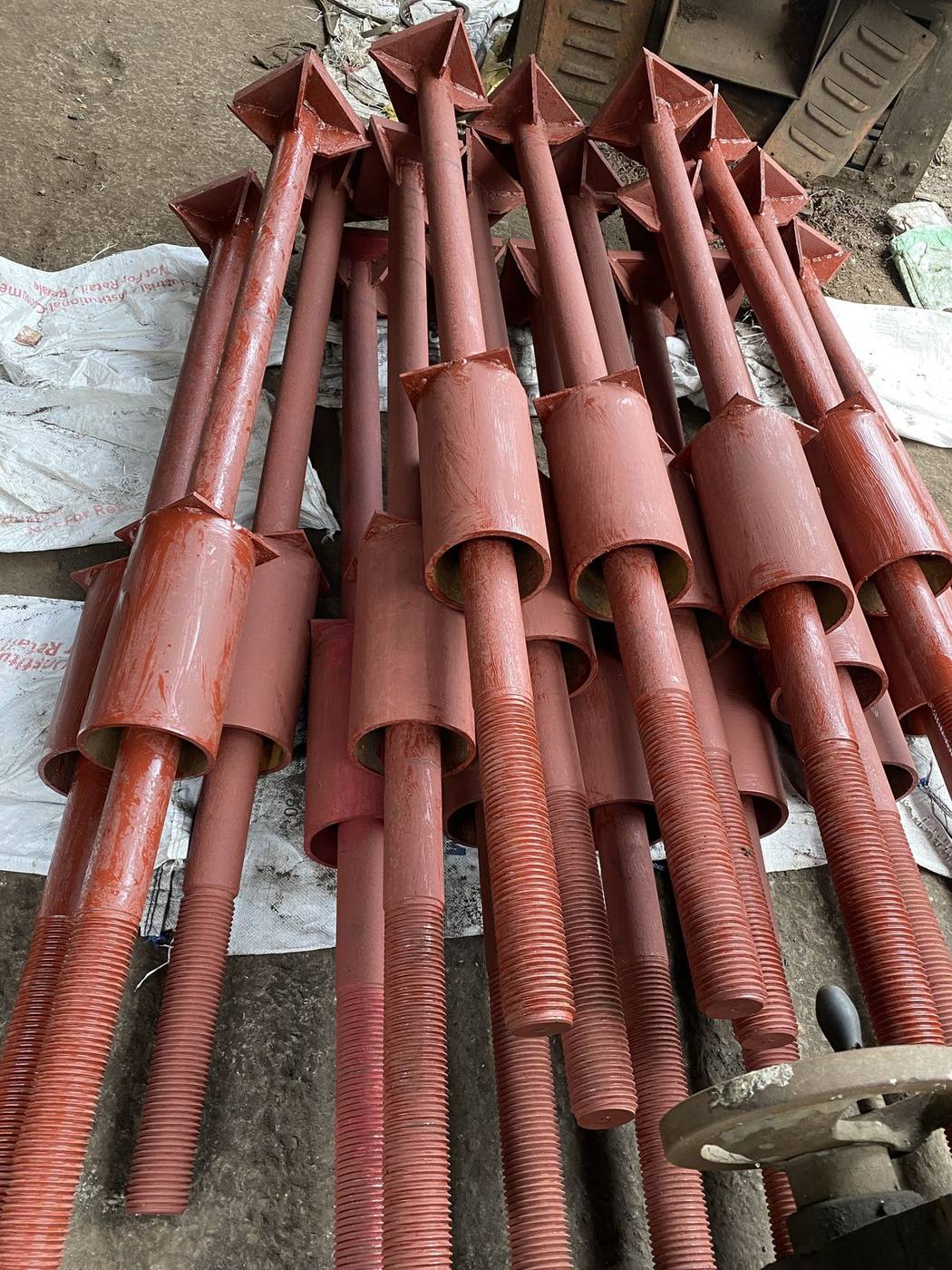 Foundation bolt assemblies in red oxide primer with pipe sleeve welded below the threaded section
